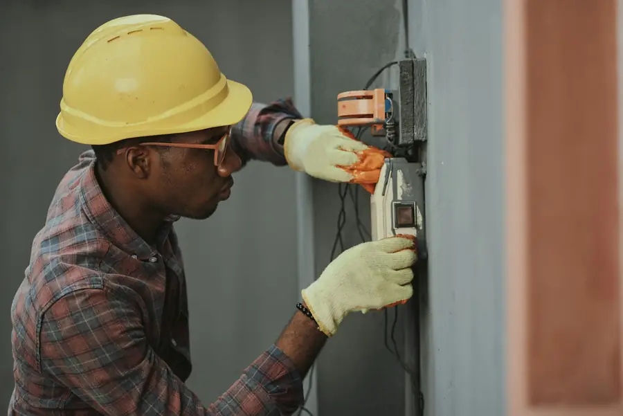 Electrician in hard hat and gloves working on electrical equipment