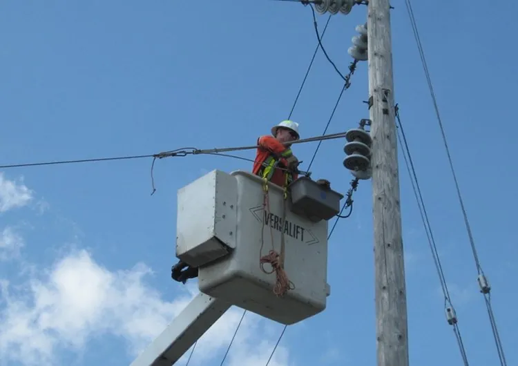 ISCOCA crew member working from a bucket truck on overhead electrical equipment in Pelham